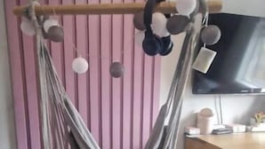 A room with a hanging chair, a wooden cabinet, and a television on the wall. - Modern 4 bedroom house Dublin 20
 (Dublin)