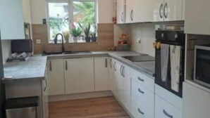 A modern kitchen with white cabinets, a stainless steel sink, and a built-in oven. - Modern 4 bedroom house Dublin 20
 (Dublin)