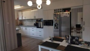 A modern kitchen with white cabinets, a stainless steel refrigerator, and a dining area with a table and chairs. - Modern 4 bedroom house Dublin 20
 (Dublin)