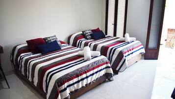 Two beds with striped bedding and pillows, a wooden headboard, and a white tiled floor.