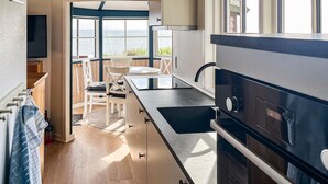 A modern kitchen with a large island, stainless steel appliances, and a view of the sea. - 2 bedroom cozy home in Esbjerg V (Esbjerg V)