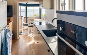 A modern kitchen with a large island, stainless steel appliances, and a view of the sea.