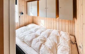 A bedroom with a wooden headboard, a bed with white bedding, and a wardrobe with two doors. - 2 bedroom cozy home in Esbjerg V (Esbjerg V)