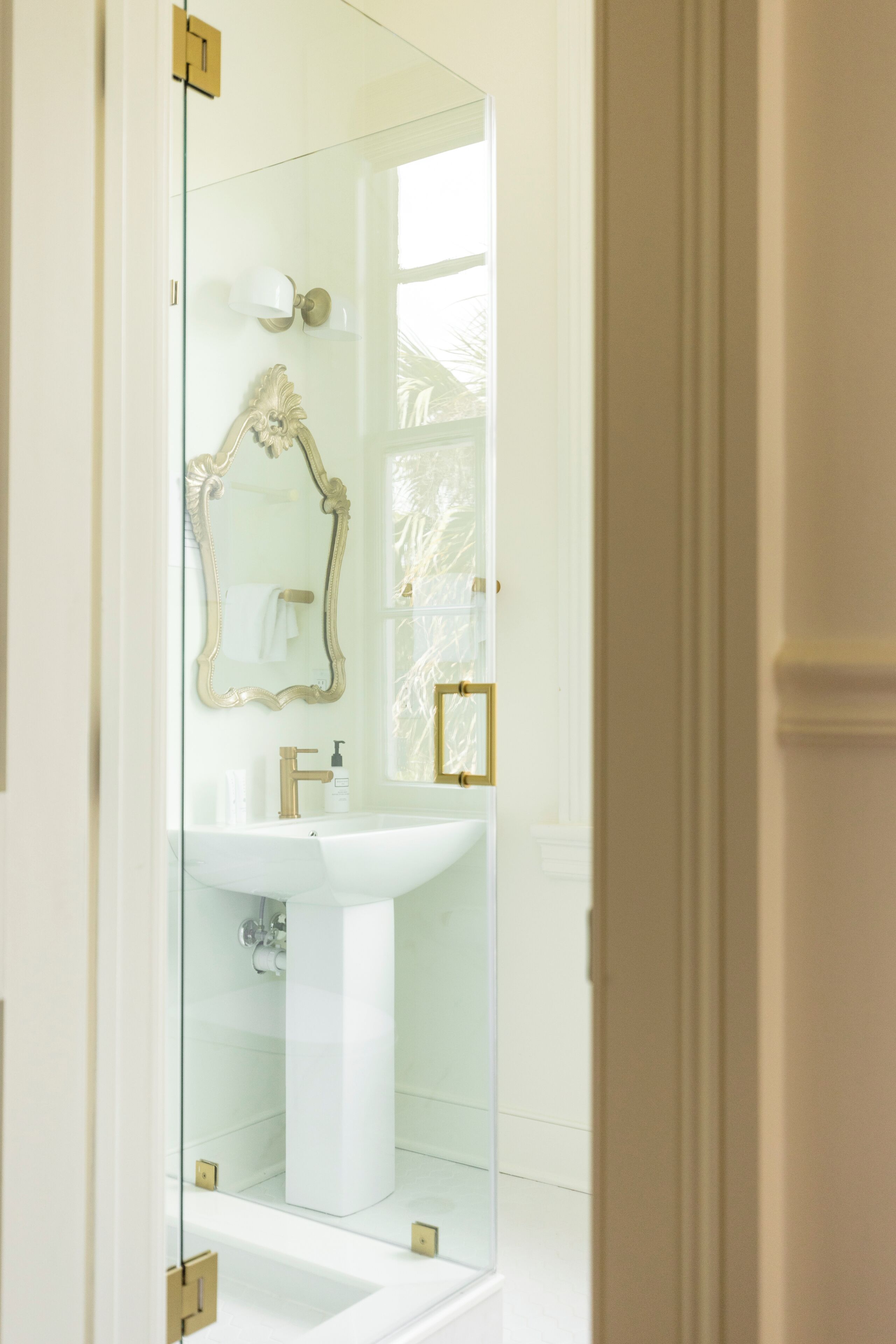 Une salle de bain avec un lavabo blanc, des robinets dorés et un miroir avec un cadre doré.