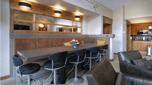 Eine moderne Küche mit Barbereich, Holzelementen und einer Sitzecke inklusive Sofa und Sesseln.
