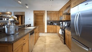 Eine moderne Küche mit Holzschränken, einem Edelstahlkühlschrank und Granitarbeitsplatten.