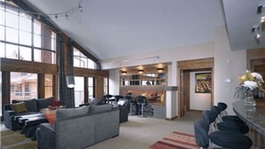 Ein großzügiger Wohnbereich mit einer großen Couch, einem Couchtisch und einer Bar mit Hockern.