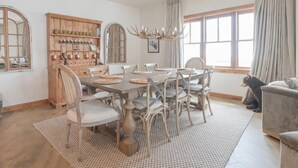A dining room with a large wooden table, multiple chairs, a chandelier, and a bear statue.