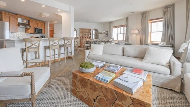A modern living room with a sofa, coffee table, and bar stools.