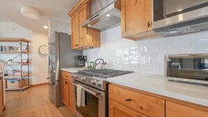 A kitchen with wooden cabinets, a stainless steel refrigerator, a gas stove, and a microwave.