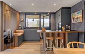 Una cocina moderna con un revestimiento de madera, un ventanal grande y una barra con taburetes.