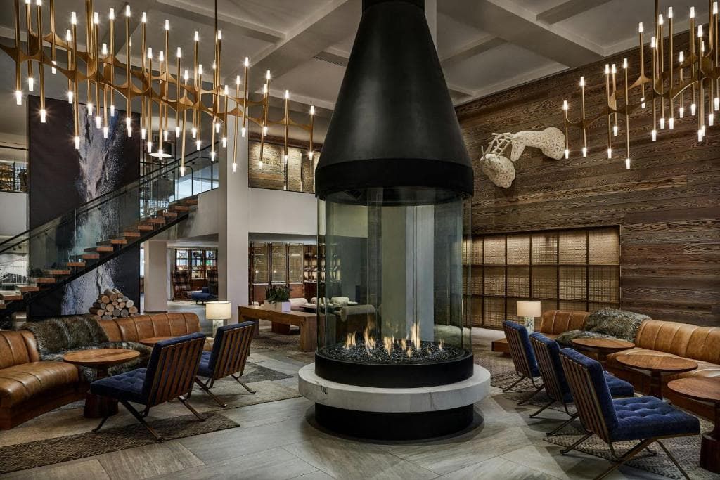 A spacious lobby with a central fire feature, comfortable seating, and a staircase.
