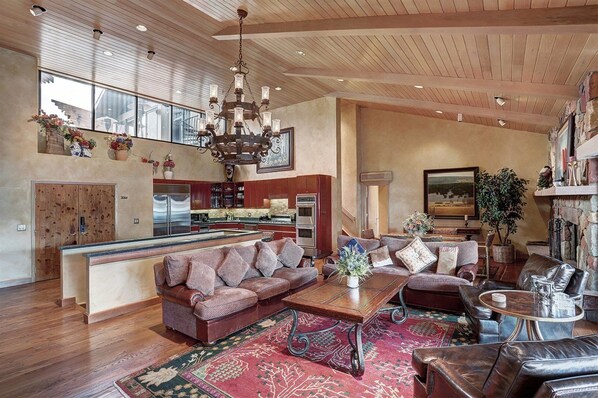 A spacious living area with a large sofa, a coffee table, and a fireplace. There is a kitchen area with modern appliances and a large island. - 4 Bedroom Luxury Residence at World-class Resort in Lionshead Village (Vail)