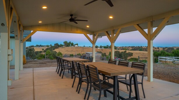 An outdoor patio with a table and chairs, ceiling fans, and a view of the countryside. - Wine Country Escape*Hot Tub*Fire Pit (Paso Robles)