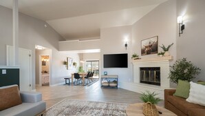 A spacious living room with a fireplace, a dining area, and a kitchen in the background. - Wine Country Escape*Hot Tub*Fire Pit (Paso Robles)
