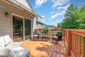Um deck de madeira com mobiliário externo e uma porta de correr que dá para um pátio.