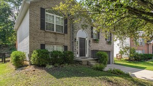A two-story brick house with a dark front door, a small porch, and a well-maintained lawn. - Modern Kentucky Retreat Near Ark & Cincinnati! (Covington)