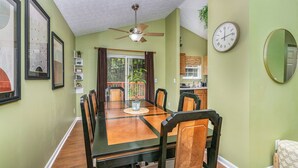 A dining area with a large table, chairs, a ceiling fan, a clock, and a mirror on the wall. - Modern Kentucky Retreat Near Ark & Cincinnati! (Covington)