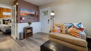 A cozy living room with a bed, a couch, a fireplace, and a painting on the wall.