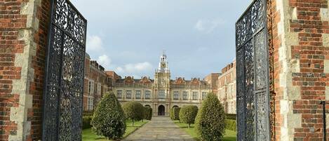 A grand entrance with ornate metal gates leading to a historic building with a central clock tower.