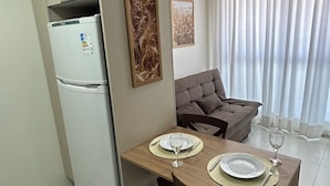 A compact living space with a kitchenette, a dining table set for two, and a sofa. - Melhores Flats - Belezinha perto do mar (João Pessoa)