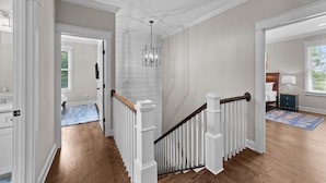 A hallway with white railings, a wooden floor, and a chandelier. - Traditional 4BR Craftsman, In DT Durham, Near Duke (Durham)