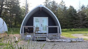 Une cabane en forme de dôme, dotée d’une véranda, d’une porte et d’une chaise.