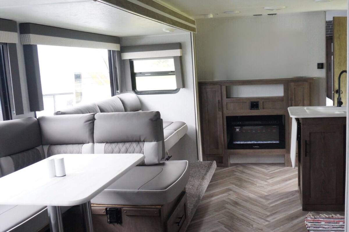 Een compact camperinterieur met een eethoek, zitplaatsen, een kitchenette en een kleine badkamer.