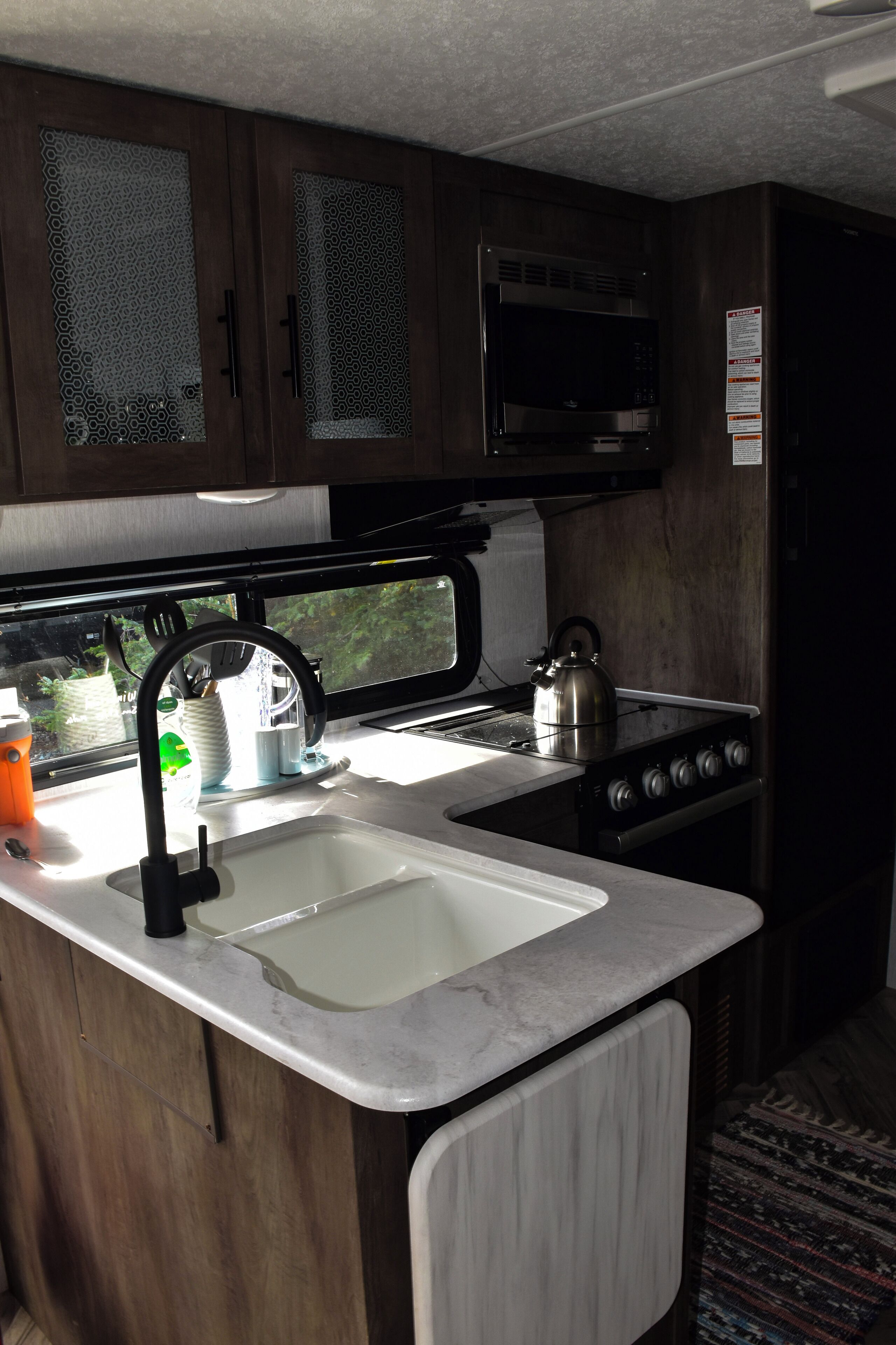 A compact kitchen with a sink, stove, and microwave.