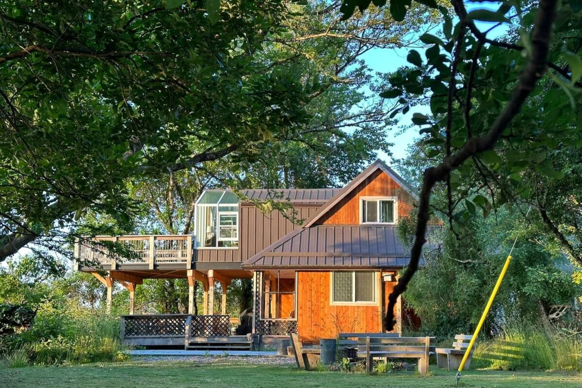 Een houten huis met balkon en glazen uitbouw.