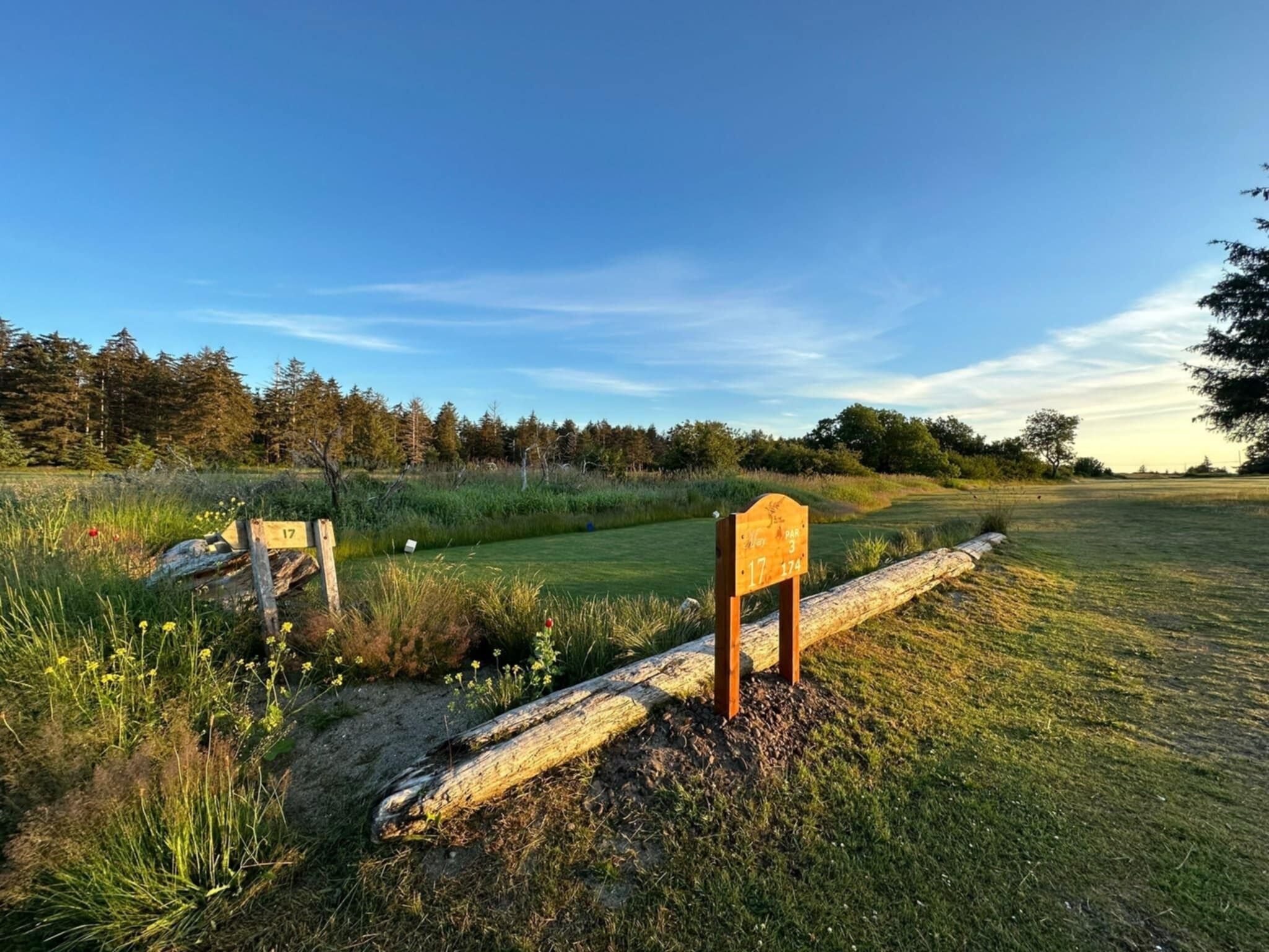 Een golfbaan met genummerde borden, een houten klapper en een bos op de achtergrond.