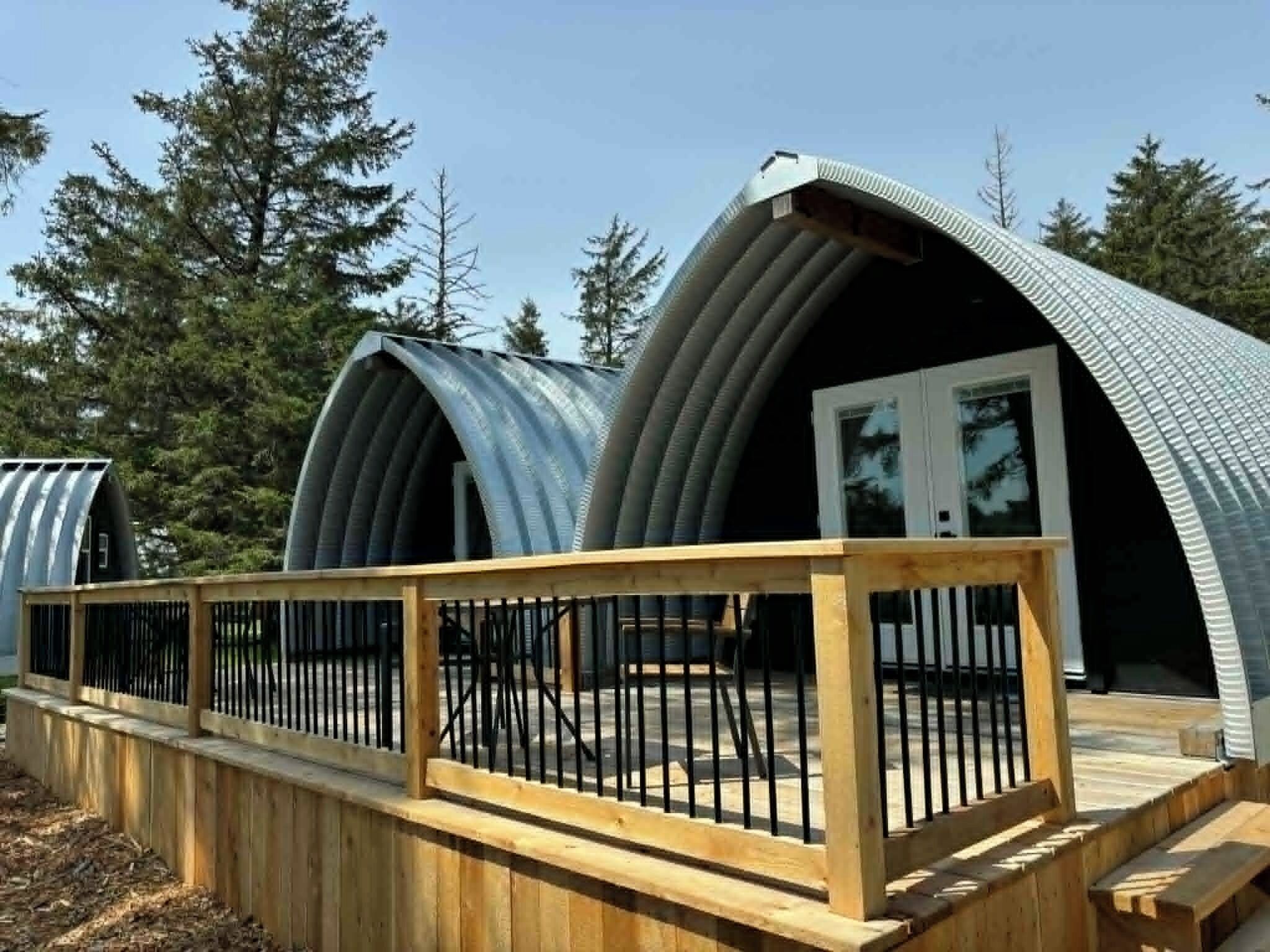 A series of dome-shaped cabins with wooden railings and a forest backdrop.