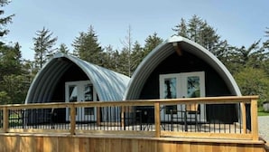Deux structures métalliques en forme d’arche, dotées de garde-corps en bois, qui font probablement partie d’un terrain de camping ou d’un centre de loisirs.