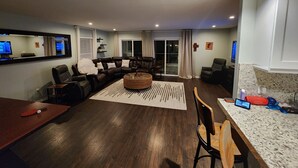 A modern living room with a sectional sofa, a coffee table, and a dining area with a table and chairs. - Intercostal channel house with boat dock and ping-pong table  (South Daytona)