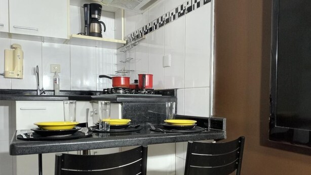 Une cuisine moderne avec des armoires blanches, un comptoir noir et deux chaises noires.