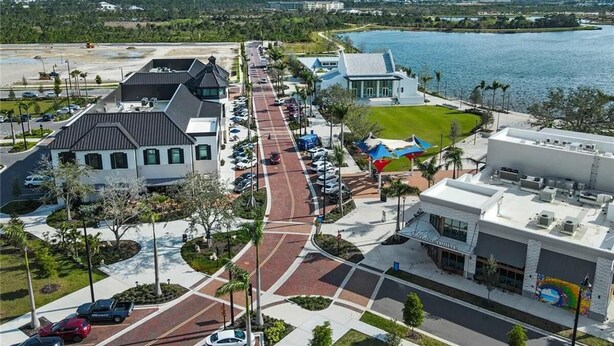 A coastal town with a main road, parked cars, and a waterfront view.