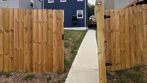 A residential area with a blue house, wooden fences, and a concrete pathway.