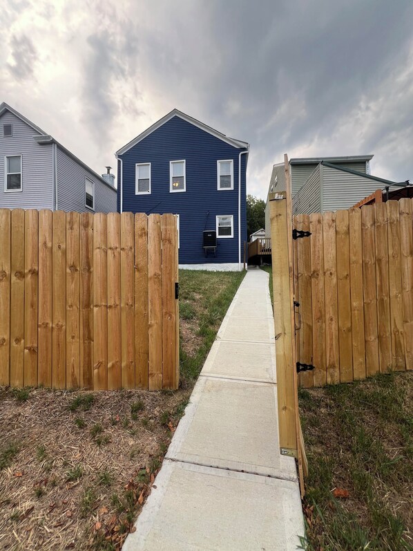 A residential area with a blue house, wooden fences, and a concrete pathway. - Central Home 3min to downtown + private parking + 10% off Ark, Aquarium, and Zoo (Covington)