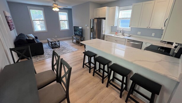A modern kitchen with a large island, white cabinets, and a dining area with a sofa and chairs.