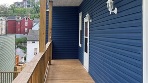 A covered wooden deck with a blue exterior wall and a white door.