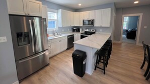 A modern kitchen with stainless steel appliances, white cabinets, and a marble countertop.