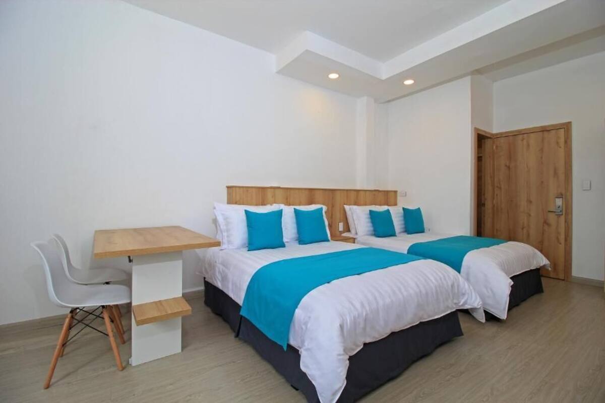 A hotel room with two beds, a desk, and a chair.