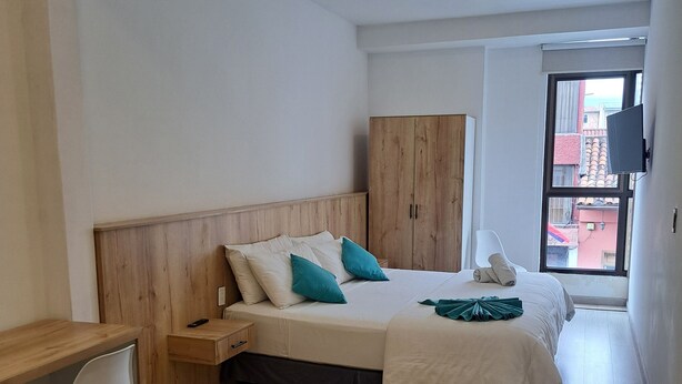 Un dormitorio con cama, escritorio y armario.