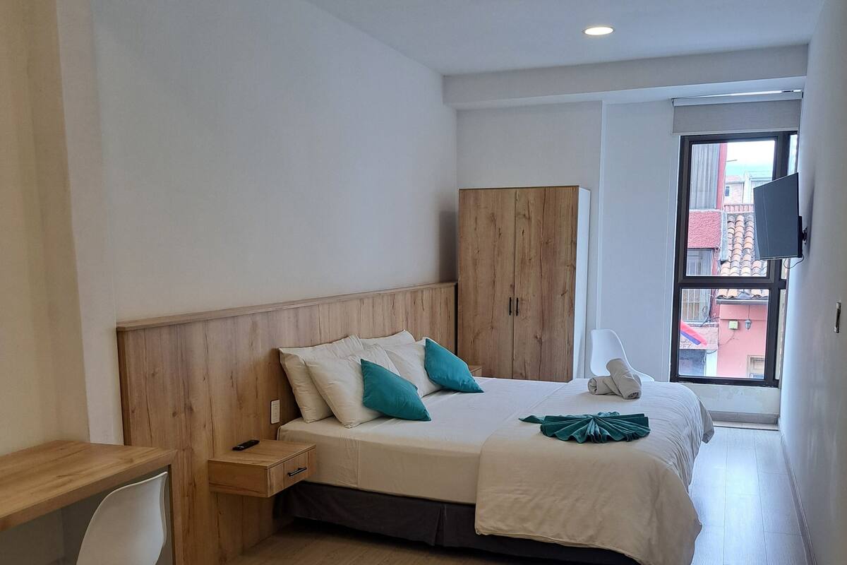 A bedroom with a bed, a desk, and a wardrobe.
