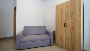Una habitación con un sofá gris, un armario de madera y un suelo de color claro.