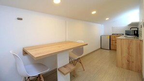 Una cocina compacta con una mesa y sillas de madera, un refrigerador y una pequeña isla con un lavamanos.