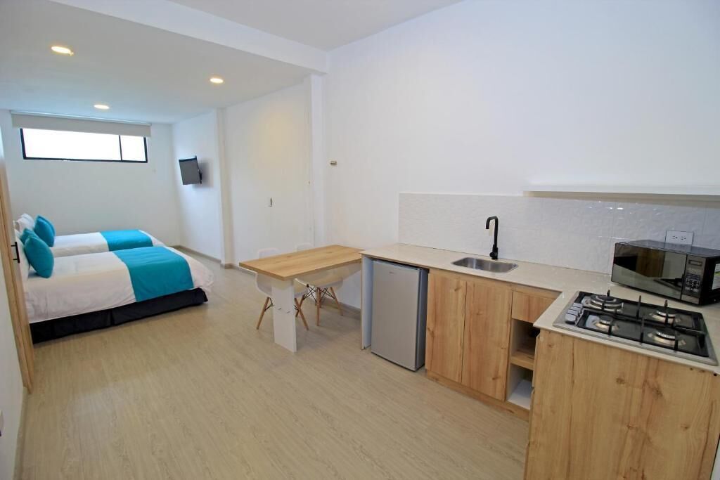 A compact room with a bed, a small kitchenette, and a window.