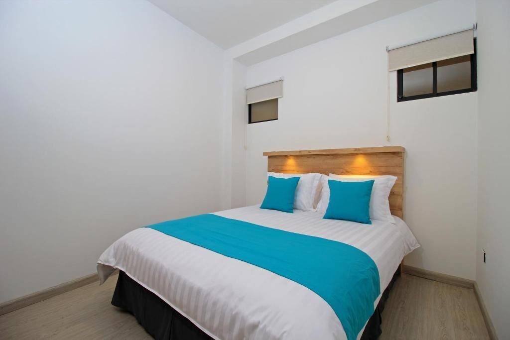 A bedroom with a bed, a headboard, and a window with blinds.