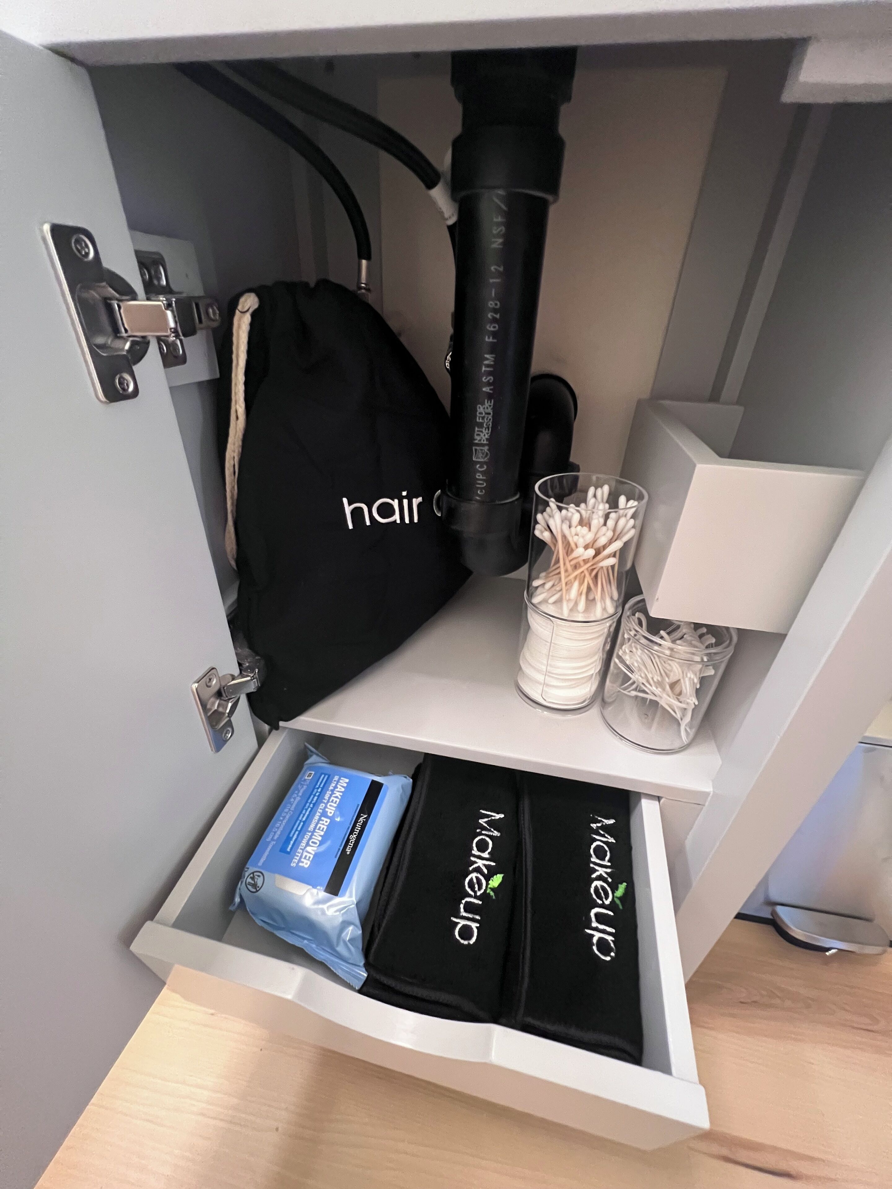 A drawer with hair care products, a hair dryer, and cotton swabs.