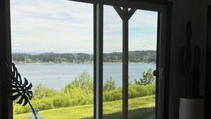 A room with a large sliding glass door leading to a view of a lake and mountains.